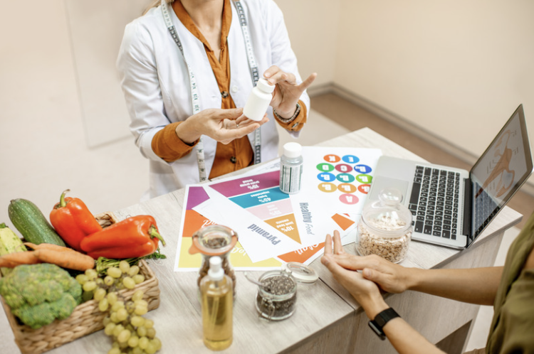 Person counseling someone on nutrition, surrounded by fruits and vegetables.